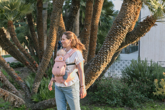 A mother and her sleeping child in front of palm trees.