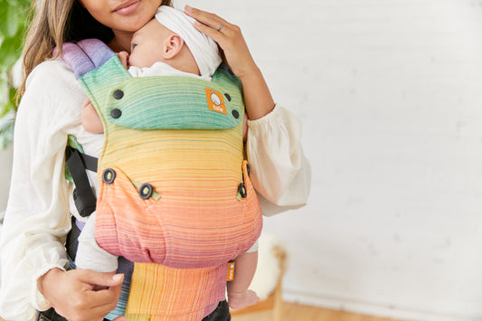 A mother carrying her child in a colourful Signature Carrier Girasol.