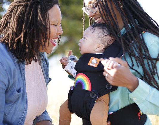 Two mothers laughing at their forward-facing baby.