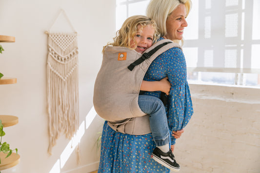 A child sitting in back-carry position on their mothers back.