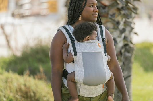 A mother carrying her child in summer, while standing in the shade.