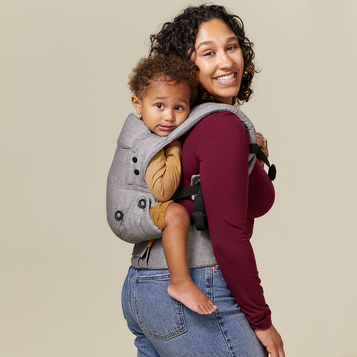 Mum carrying her infant in Tula Linen Ash Explore carrier on her back