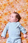 A photo of a newborn on Tula Sunflower Swaddle Blanket made from tencel