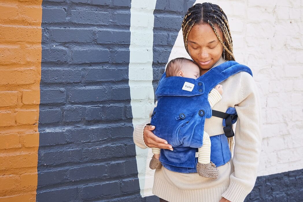 Joga teacher Heaven carrying her daughter Soleil in a Tula Velour Explore Sapphire baby carrier