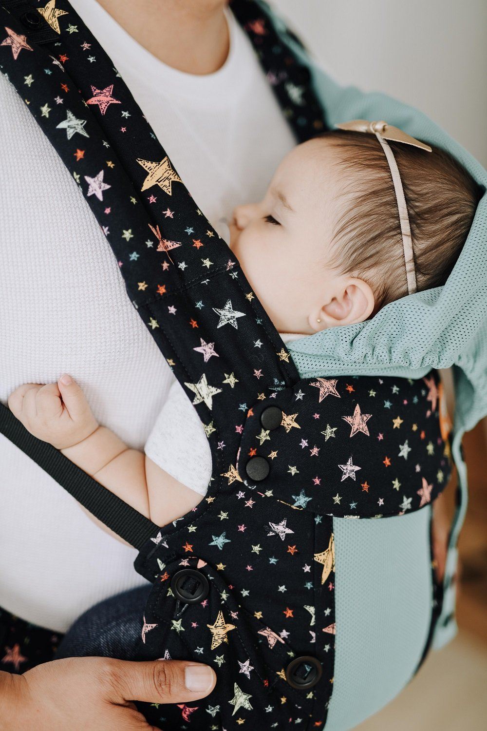 A sleeping baby while sitting in the Explore Baby Carrier Coast Rainbow Stars.