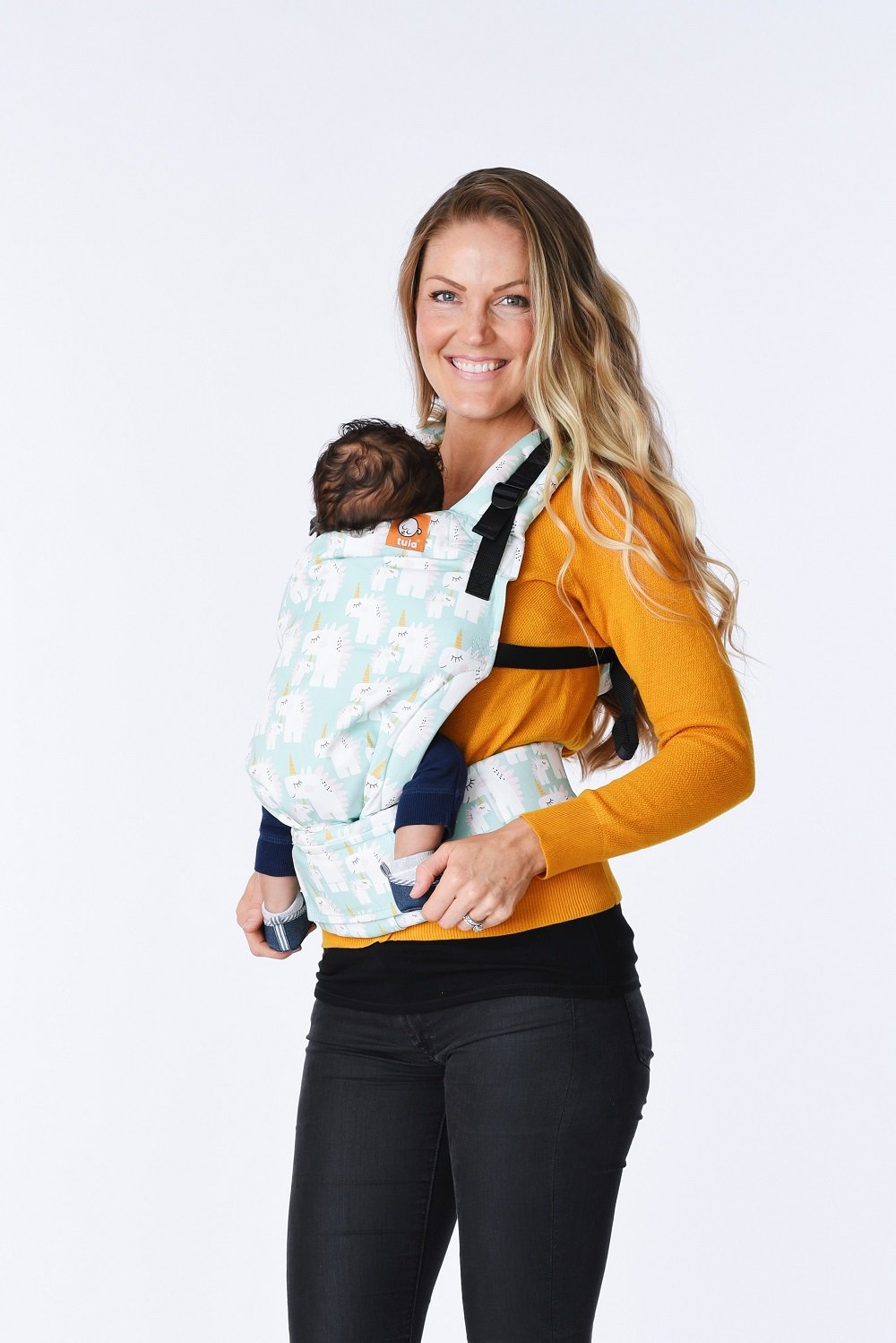 A baby and their mother using the ergonomic Tula Free-to-Grow Baby Carrier Unisaurus in front-carry position.