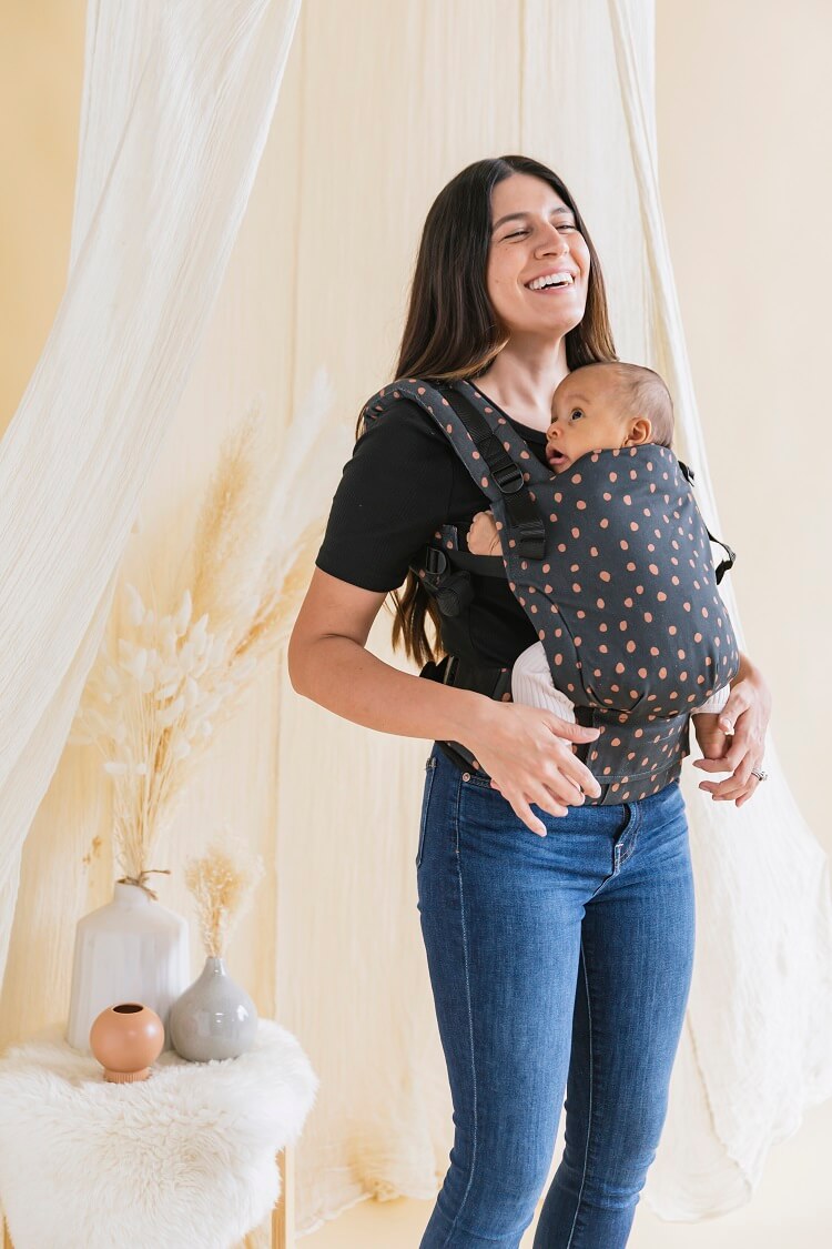 A baby sitting in the ergonomic Free-to-Grow Baby Carrier Ginger Dots.