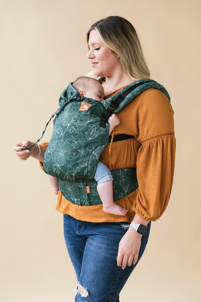 A baby sleeping in the ergonomic Tula Free-to-Grow Baby Carrier Harper in a front-carry position.