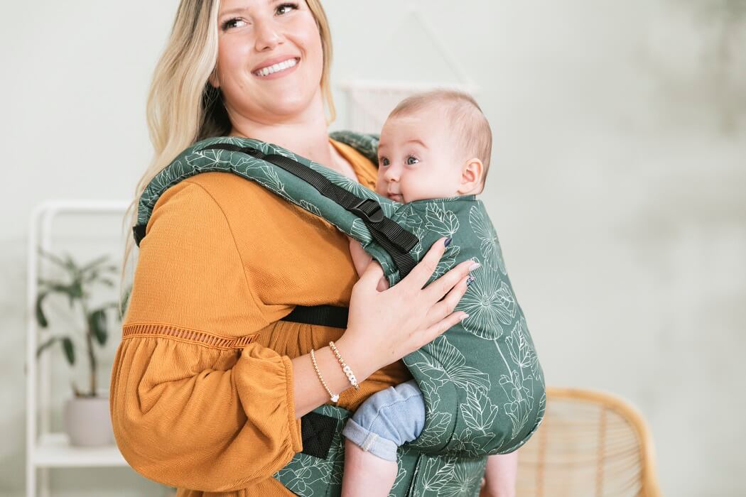 A baby sitting in the ergonomic Tula Free-to-Grow Baby Carrier Harper in a front-carry position.