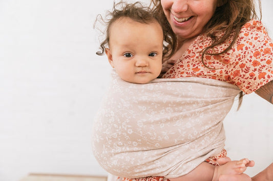 Eine glückliche Betreuungsperson und ihr Kind, während sie einen Tula Ring Sling benutzen.