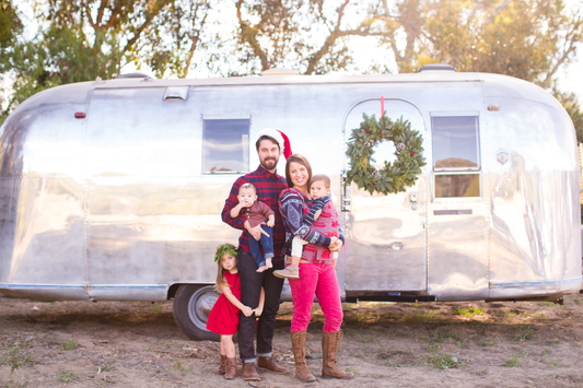 Eine festliche Familie vor einem silbernen Camper.