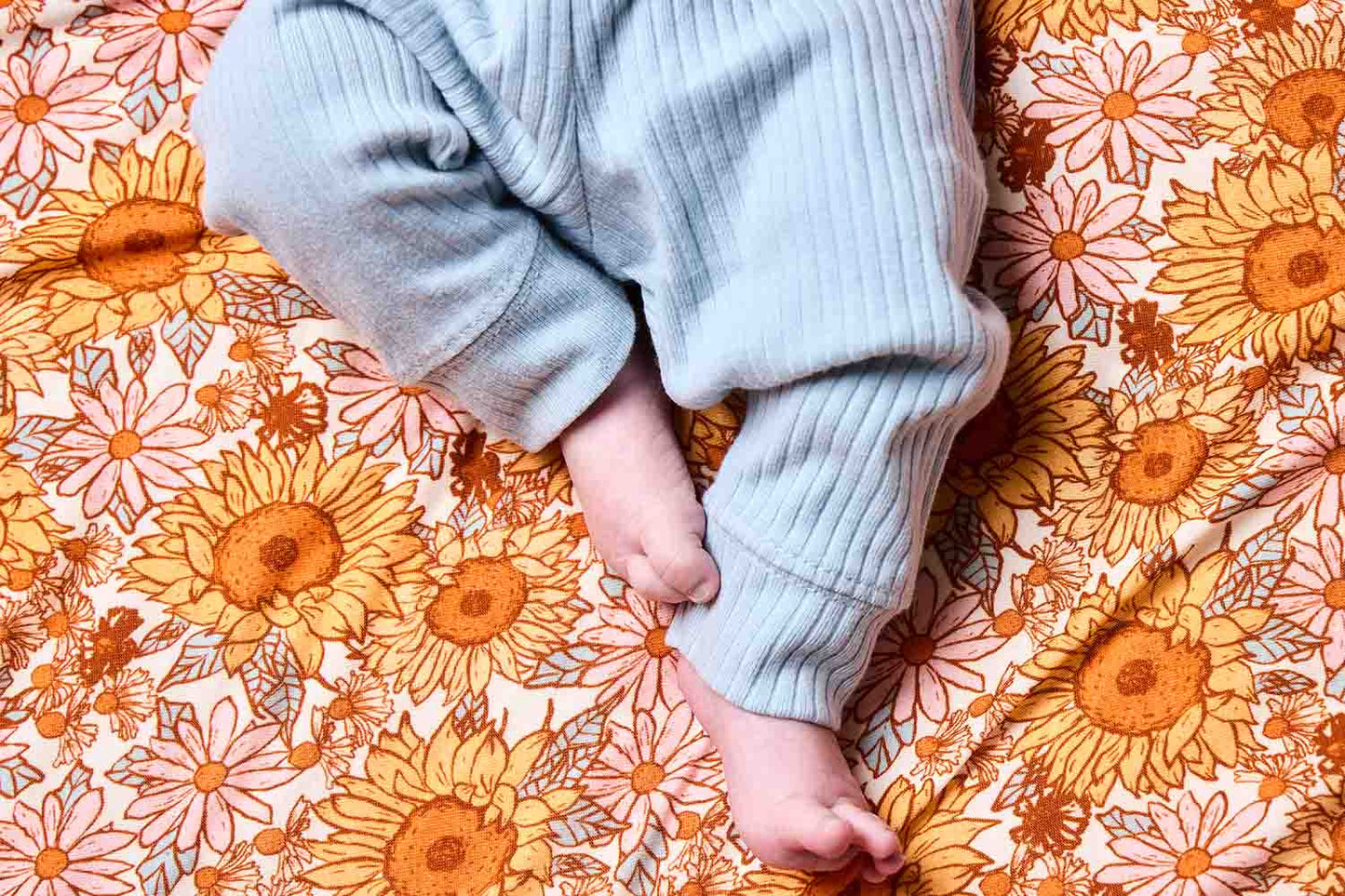 Ein Foto von Babyfüßen auf der Tula Sunflower Wickeldecke aus Tencel