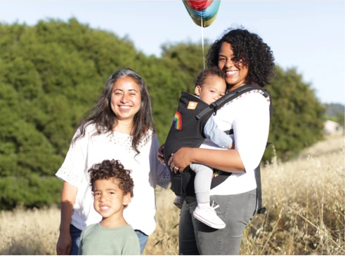 Una familia feliz de cuatro personas de pie fuera.