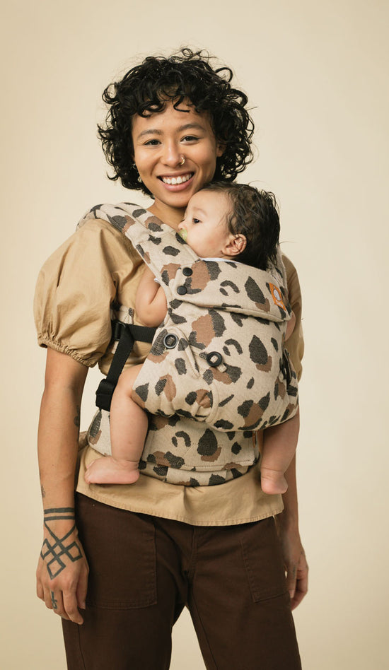 Mamá feliz porteando a su bebé en el portabebés para recién nacidos Tula Explore 
