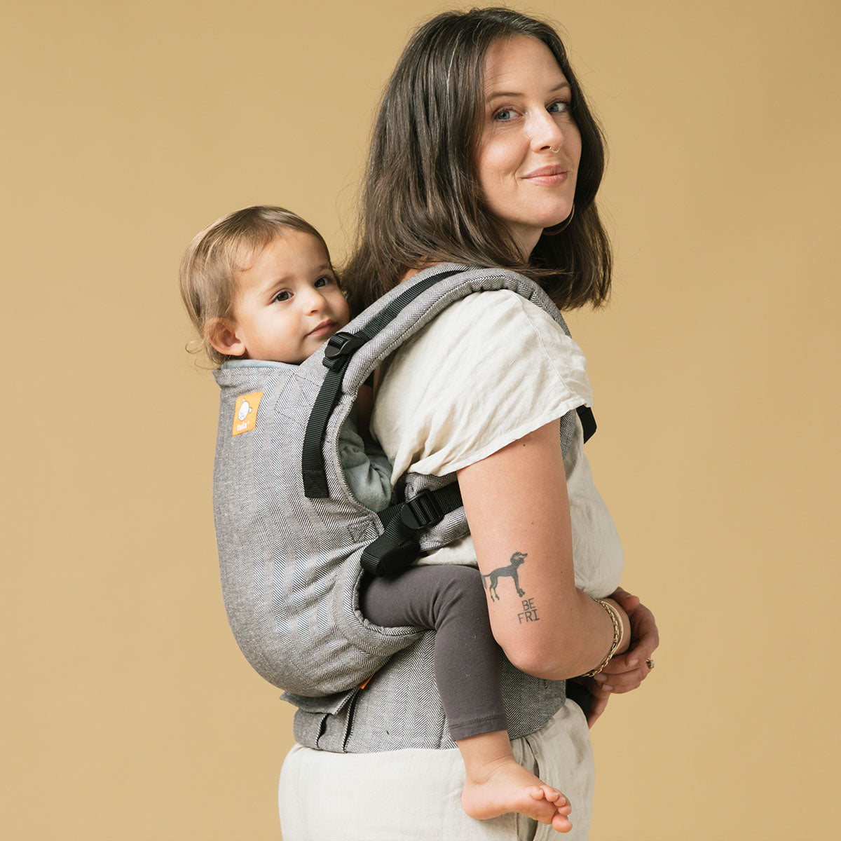 Äiti kantaa lastaan selässään Tula Free-to-Grow kantorepussa