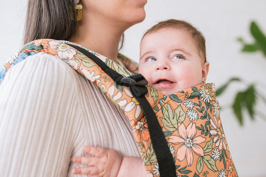 Gros plan sur un enfant souriant dans un porte-bébé Tula.