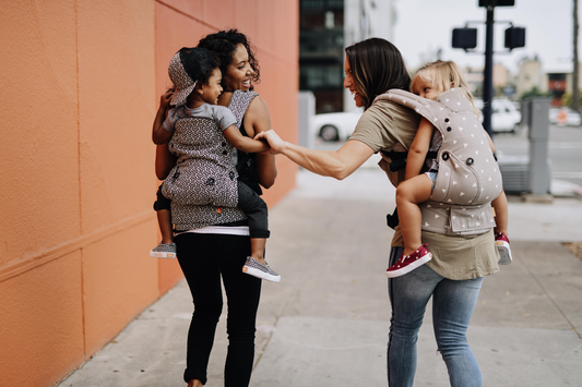 Due madri che portano entrambe i loro figli sulla schiena.