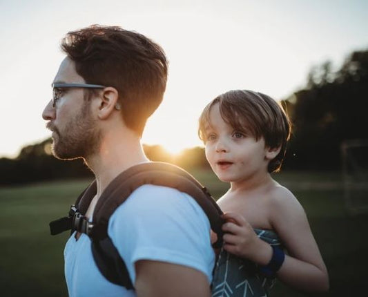 Un padre che trasporta il figlio in posizione di posteriore.