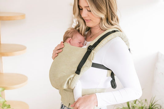 Een moeder draagt haar pasgeborene in een Tula draagzak.