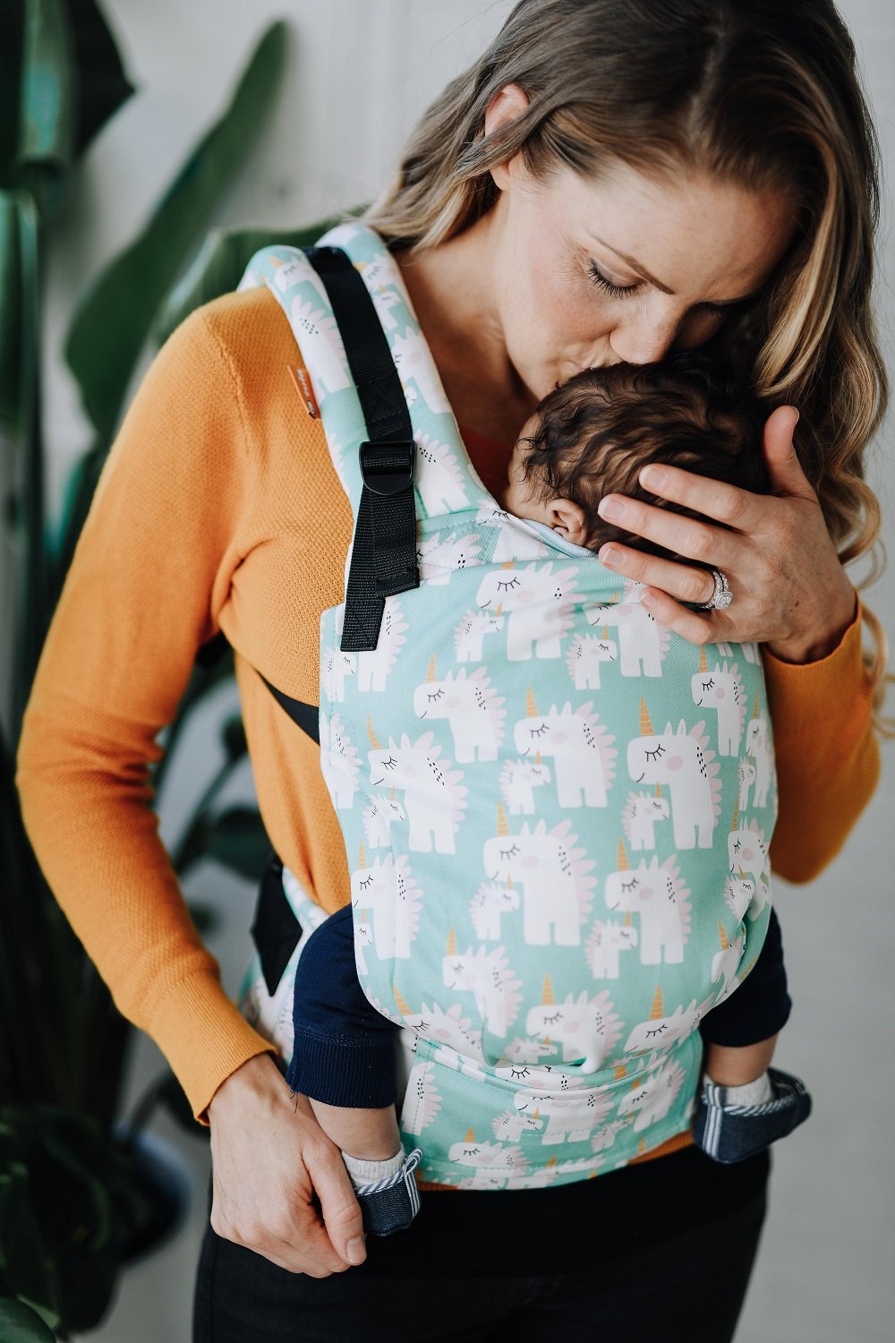 Een baby en zijn moeder gebruiken de ergonomische Tula Free-to-Grow Baby Draagzak Unisaurus in buikdragerpositie.