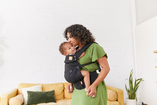 Uśmiechnięty duet matka-dziecko korzystający z nosidełka Tula Urbanista w pozycji przodem do kierunku jazdy.