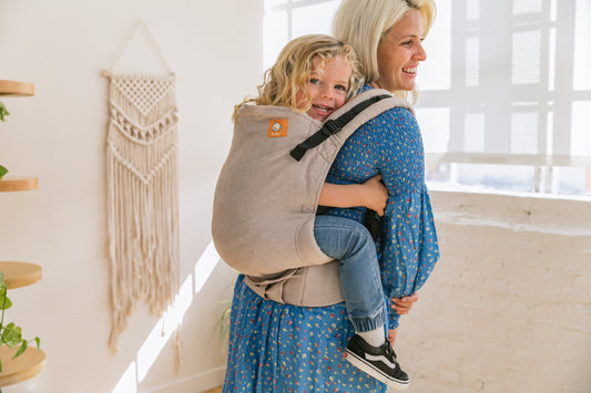 Dziecko siedzące w pozycji do noszenia na plecach matki.