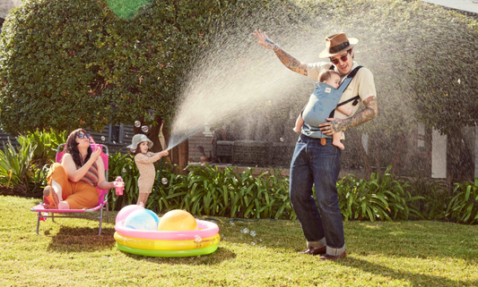 Rodzina bawiąca się w słoneczny, gorący dzień, tata i dziecko w nosidełku