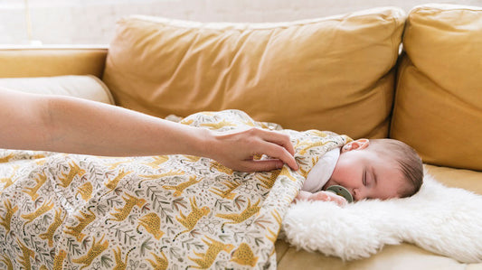 Um bebé a dormir debaixo do cobertor Tula Prowl Baby Blanket