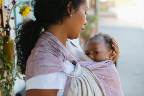 Uma mãe a amamentar o seu filho com uma funda Tula Ring Sling.