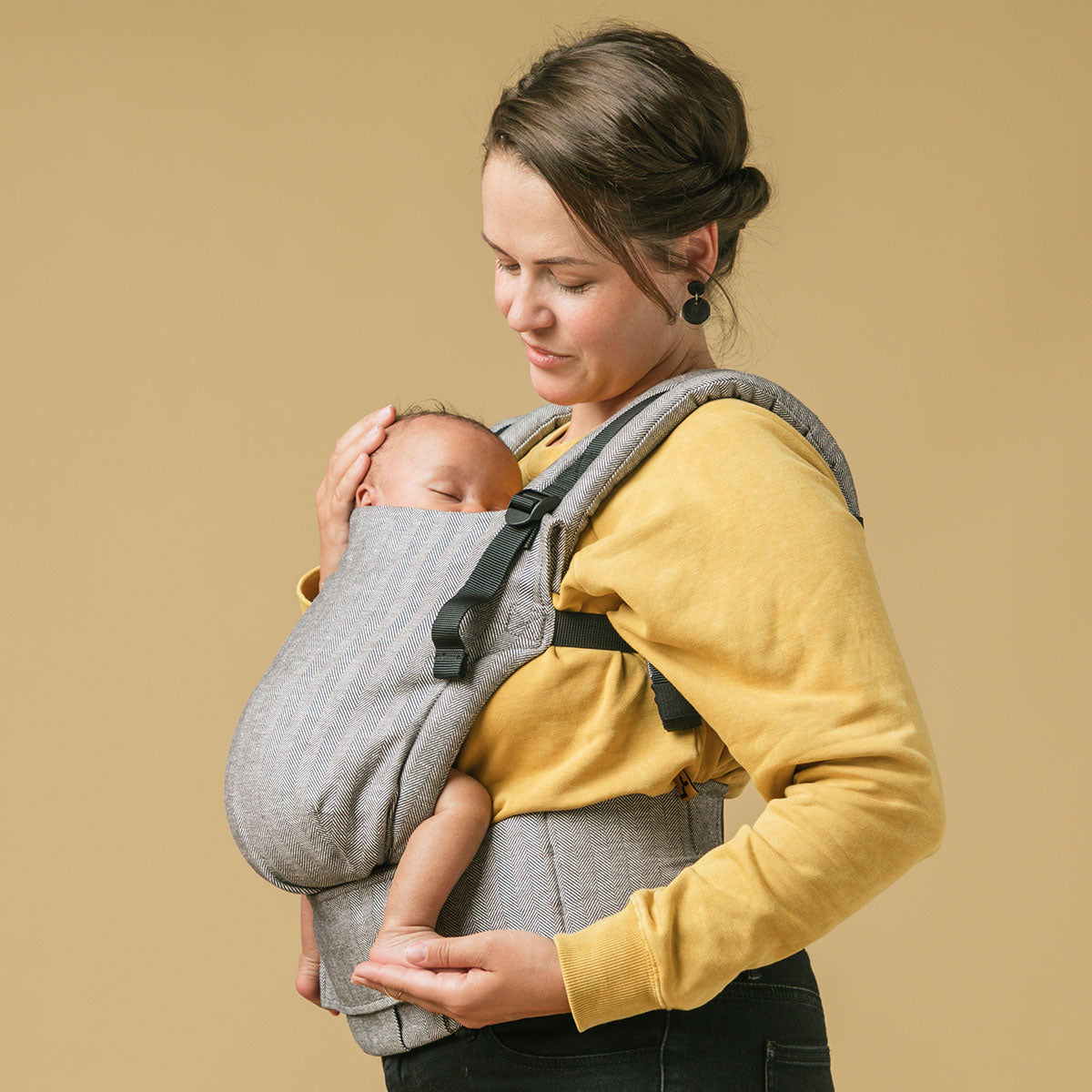 A mãe carrega o seu bebé numa posição virada para dentro noPorta-bebés Tula Free-to-Grow